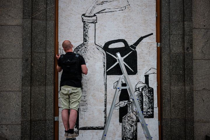 L'artiste de rue ukrainien Gamlet Zinkivskyi peint sur une planche de bois dans une rue de Kharkiv, le 16 mai 2022, en pleine invasion de l'Ukraine par la Russie. (DIMITAR DILKOFF / AFP)