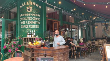 Gérald, employé dans un bistrot et épicerie corse parisien, craint de perdre des clients, qui n'auront pas la patience d'attendre quelques instants à l'entrée si des clients devant eux cherchent leur pass sanitaire sur leur téléphone.&nbsp; (PAOLA GUZZO / RADIO FRANCE)