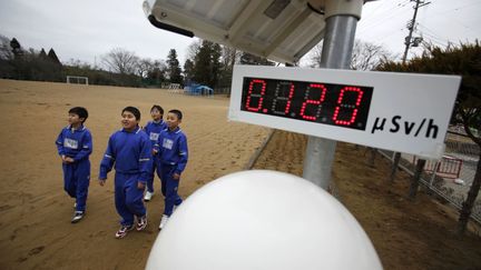 Des &eacute;coliers passent devant un compteur Geiger install&eacute; dans la cour de leur &eacute;tablissement situ&eacute; &agrave; 21 km de la centrale nucl&eacute;aire de Fukushima (Japon), le 8 mars 2012. (TORU HANAI / REUTERS)