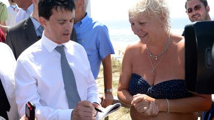 Le ministre de l'Int&eacute;rieur, Manuel Valls, signe un autographe lors d'un d&eacute;placement &agrave; Mimizan (Landes), le 1er ao&ucirc;t 2013. (JEAN-PIERRE MULLER / AFP)