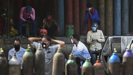 Plusieurs personnes attendent pour remplir des&nbsp;bouteilles d'oxygènes, nécessaires à la prise en charge des patients hospitalisés pour le Covid-19, à&nbsp;Allahabad (Inde), le 24 avril 2021. (SANJAY KANOJIA / AFP)