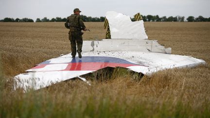 Un s&eacute;paratiste pro-russe se tient sur un morceau de l'appareil, qui assurait la liaison entre Amsterdam et Kuala Lumpur. (MAXIM ZMEYEV / REUTERS)