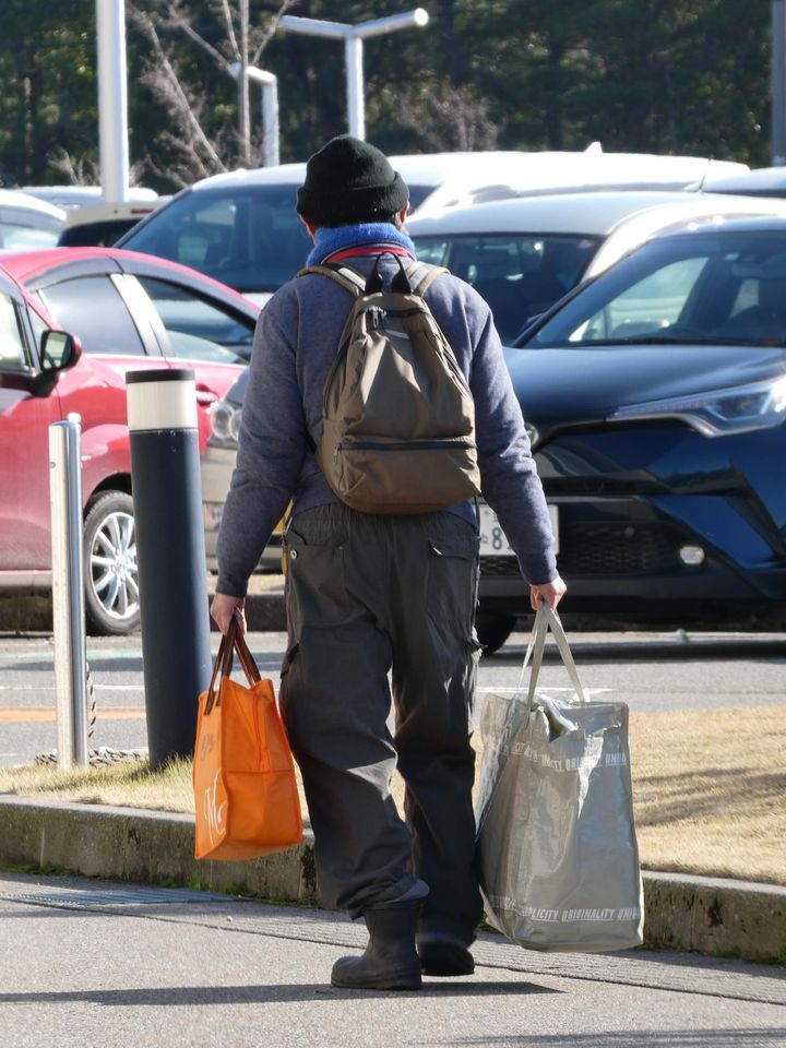 Norimitsu Funamoto, refugee from the town of Suzu, photographed from behind with his bags in the parking lot of the Ishikawa sports center in Kanazawa transformed into a site for evacuees (KARYN NISHIMURA / RADIO FRANCE)