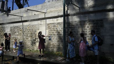 Des personnes se rafraîchissent sous des brumisateurs durant la canicule, le 10 août 2022. (MAGALI COHEN / HANS LUCAS / AFP)