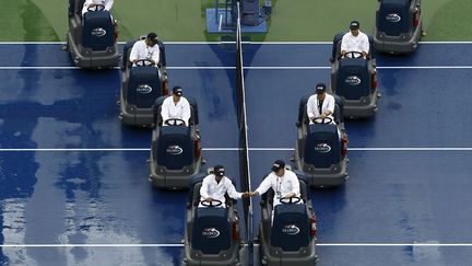 Des employ&eacute;s s&egrave;chent un court de tennis apr&egrave;s une interruption en raison de la pluie lors de l'open de New York (Etats-Unis), le 31 ao&ucirc;t 2014. (EDUARDO MUNOZ / REUTERS)