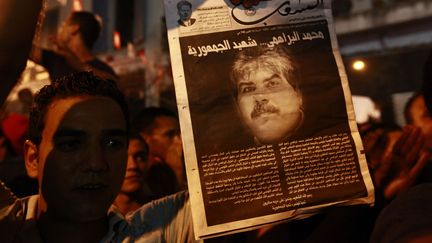 Un manifestant brandit un journal annon&ccedil;ant la mort du d&eacute;put&eacute; d'opposition Mohamed Brahmi &agrave; Tunis, le 25 juillet 2013. (ANIS MILI / REUTERS)