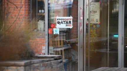 Une affiche appelant au boycott de la Coupe du monde au Qatar sur la porte d'entrée d'un bar à Hambourg, en Allemagne, le 23 novembre 2022. (JONAS WALZBERG / DPA / MAXPPP)