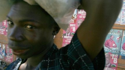 Un jeune homme passe près des affiches des candidats à la présidentielle le 3 février 2011 à Port-au-Prince (AFP - HECTOR RETMAL)