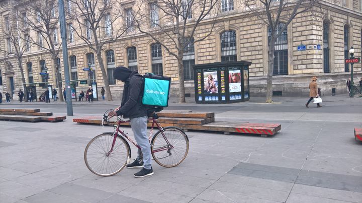 Un livreur (qui n'a pas été interrogé dans le cadre de notre article) attend une commande en consultant son téléphone portable, place de la République, à Paris. (F. MAGNENOU / FRANCEINFO)