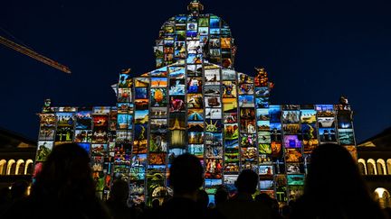 Des spectateurs assistent &agrave; l'illumination du parlement suisse &agrave; l'occasion des projections de la compagnie fran&ccedil;aise "Spectaculaires Allumeurs d'images" &agrave; Bern (Suisse), le 17 octobre 2014. (FABRICE COFFRINI / AFP)