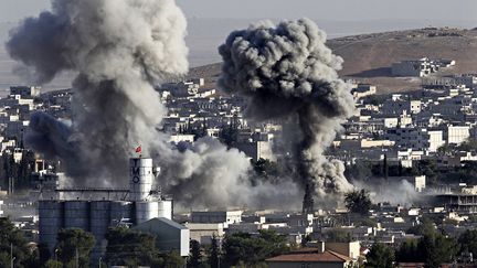 Une colonne de fum&eacute;e s'&eacute;chappe de la ville syrienne de Kobani, le 15 octobre 2014, en proie &agrave; des combats entre les jihadistes de l'Etat islamique et les forces kurdes.&nbsp; (HUSEYIN SARI-XINHUA / NOTIMEX / AFP)