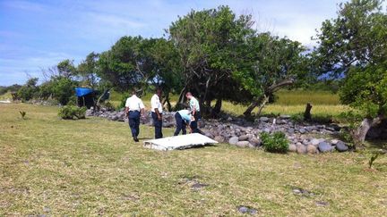 Des enqu&ecirc;teurs autour du d&eacute;bris retrouv&eacute; &agrave; Bois-Rouge, sur la commune de Saint-Andr&eacute; de La R&eacute;union, le 30 juillet 2015. (JEAN-RÉGIS RAMSAMY / RÉUNION 1ÈRE)