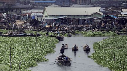 Des barques naviguent au milieu des jacinthes d'eau dans un bidonville de Lagos. (SUNDAY ALAMBA/NBC/AP/SIPA / AP)