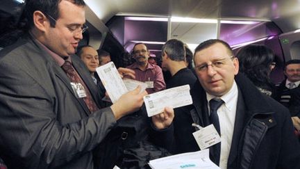 Des usagers de la ligne Angers-Le Mans-Paris avec leurs badges "Abonné en grève" (18 janvier 2011) (AFP / Jean-François Monier)