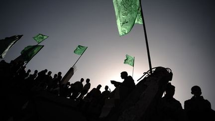 Militants du Hamas brandissant le drapeau du mouvement sur des ruines à Gaza après les bombardements israéliens (© AFP/OLIVIER LABAN-MATTEI)