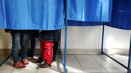 Trois enfants accompagnent leur m&egrave;re dans un isoloir, le 23 mars 2014, pour le premier tour des municipales, &agrave; Nantes (Loire-Atlantique). (JEAN-SEBASTIEN EVRARD / AFP)