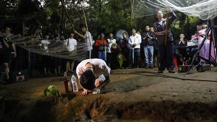 Sans aucune nouvelles de leurs enfants depuis trois jours, les familles prient devant l'entrée de la grotte. (KRIT PHROMSAKLA NA SAKOLNAKORN / AFP)