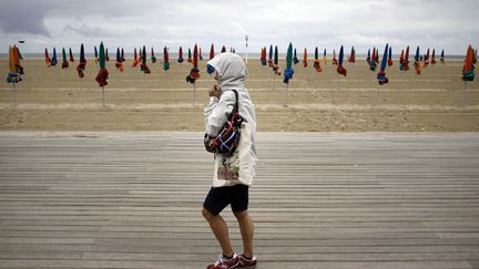 Une femme brave le mauvais temps sur les planches de Deauville (Calvados), le 10 juillet 2012. (CHARLY TRIBALLEAU / AFP)