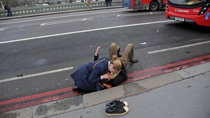 Une femme vient en aide à une personne blessée lors de l'attaque à Londres (Royaume-Uni), le 22 mars 2017.&nbsp; (TOBY MELVILLE / REUTERS)