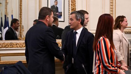 Le ministre de l'Intérieur, Gérald Darmanin, salue le secrétaire général du syndicat Unité SGP Police-FO, Grégory Joron, avant une réunion avec les organisations syndicales à l'hôtel Beauvau (Paris), le 27 juillet 2023. (BERTRAND GUAY / POOL / AFP)