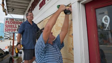 Men install wooden panels to protect windows on Treasure Island (Florida) with the arrival of Hurricane Milton, placed in category 4, on October 7, 2024. (BRYAN R. SMITH / AFP)