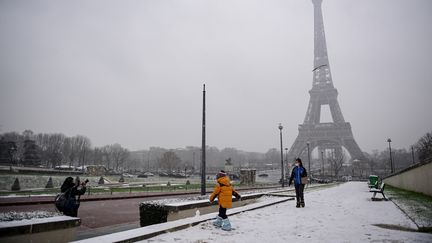 Des Parisiens jouent dans la neige non loin de la Tour Eiffel, le 16 janvier 2021. (MARTIN BUREAU / AFP)