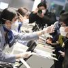 Une employée prend la température d'un passager lors du check-in avant un vol pour Wuhan, le 31 janvier 2020&nbsp;à l'aéroport Haneda de Tokyo (Japon). (MASAMINE KAWAGUCHI / YOMIURI / AFP)