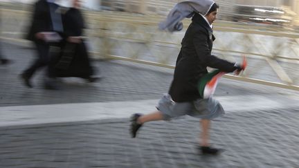 Une religieuse court place Saint-Pierre (Vatican) afin d'&ecirc;tre bien plac&eacute;e pour assister &agrave; la messe inaugurale du pape Fran&ccedil;ois, le 19 mars 2013. (MAX ROSSI / REUTERS)