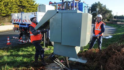 Des agents d'Enedis remplacent un transformateur à Tregunc, dans le Finistère, après le passage d'une tempête, le 13 janvier 2017. (FRED TANNEAU / AFP)