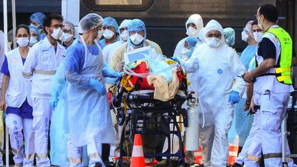 Des soignants accompagnent un patient, le 10 avril 2020, vers la gare de Bordeaux (Gironde). (MEHDI FEDOUACH / AFP)