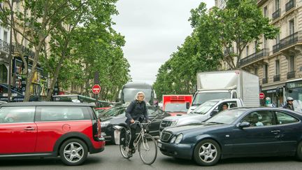 Un vélo au milieu de voitures à Paris en 2015.&nbsp; (BRUNO LEVESQUE / MAXPPP)