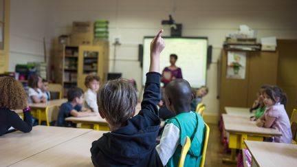 Un élève lève la main dans une école parisienne, en 2014. (FRED DUFOUR / AFP)