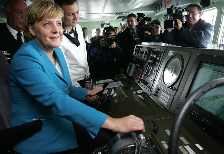 Angela Merkel &eacute;coute les instructions d'un marin &agrave; bord de la fr&eacute;gate "Sachsen", sur une base navale de la mer Baltique, le 31 ao&ucirc;t 2006. (CHRISTIAN CHARISIUS / AFP)