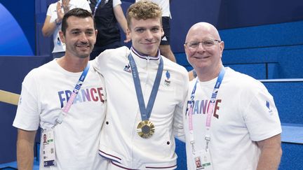 Léon Marchand entouré de ses entraîneurs, Bob Bowman (à droite) et Nicolas Castel (à gauche) après sa victoire sur le 200 m 4 nages à la Défense Arena, le 2 août 2024. (KEMPINAIRE STEPHANE / KMSP)