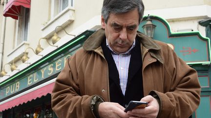 François Fillon consulte son smartphone à Sablé-sur-Sarthe, le 20 mars 2015. (JEAN-FRANCOIS MONIER / AFP)