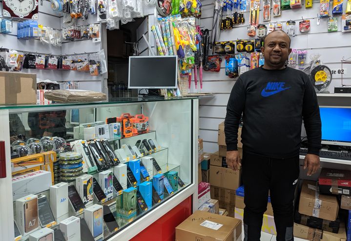 Ataur Rahman pose devant des colis, dans sa boutique d'informatique située dans le 15e arrondissement de Paris, le 18 décembre 2019.&nbsp; (CHARLOTTE CAUSIT / FRANCEINFO)