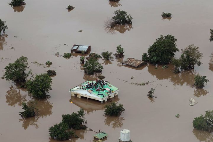 A Beira, au Mozambique,&nbsp;des habitants sont réfugiés sur le toit d'une maison, dans un quartier inondé au passage d'Idai, le 18 mars 2019. (RICK EMENAKET / MISSION AVIATION FELLOWSHIP / AFP)