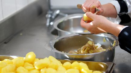 Une cuisinière épluche des pommes de terre, dans la cantine de Vieille Chapelle (Pas-de-Calais), le 3 octobre 2016. (MAXPPP)