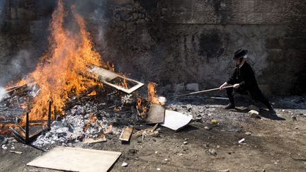 Un jeune juif ultra-orthodoxe jette du pain dans un feu alors que d&eacute;butent les c&eacute;l&eacute;brations de Pessa'h &agrave; J&eacute;rusalem (Isra&euml;l), le 14 avril 2014. (MAXPPP)