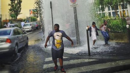 Des enfants jouent sous l'eau d'une bouche &agrave; incendie rue de Meaux, &agrave; Paris, le 4 juillet 2015. (ELODIE DROUARD / FRANCETV INFO)