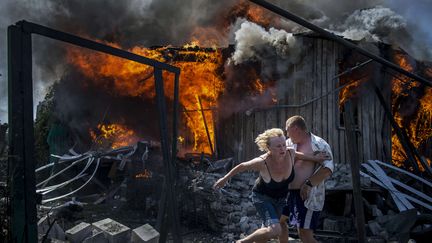 Projet de long-terme, premier prix. &nbsp;
Dans ce projet intitulé "Jours noirs de l'Ukraine", Valery Melnikov a capturé en image les vies chamboulées des victimes civiles du conflit dans le Donbass. Dans cette photo, une femme et un homme s'enfuient d'une maison en feu, détruite par une attaque aérienne sur le village de&nbsp;Luhanskaya.&nbsp; (VALERY MELNIKOV/AP/SIPA / AP)