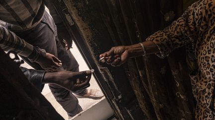 Un homme achète&nbsp;une cigarette à une vendeuse à la sauvette quelque part en Afrique du Sud le 9 avril 2020, pendant le confinement lié au coronavirus. Les autorités ont interdit la vente de cigarettes pendant cette période de confinement. (EMMANUEL CROSET / AFP)