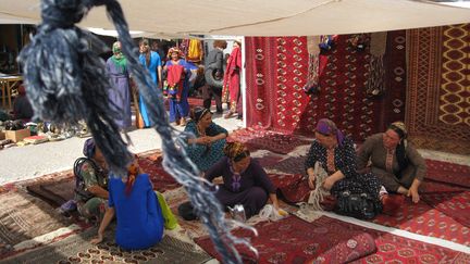 Des femmes turkmènes assises sur des tapis traditionnels au marché de&nbsp;Tolkuchka à Ashgabat&nbsp;en&nbsp;juin 2008 (DMITRY KOSTYUKOV / AFP)