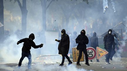 Un manifestant lance une pierre alors que des nuages ​​de gaz lacrymogènes se lèvent lors d'une manifestation en marge d'une&nbsp;manifestation du&nbsp;1er-Mai, à Paris,&nbsp;en 2018. (ALAIN JOCARD / AFP)