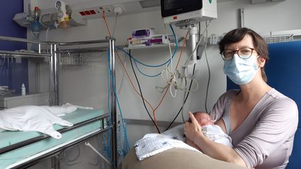 Aurélie, porteuse du Covid-19 au moment de l'accouchement, tient dans ses bras&nbsp;Ary, l'un de ses jumeaux,&nbsp;à la maternité de l'hôpital Robert Debré (Paris). (SOLENNE LE HEN / RADIOFRANCE)