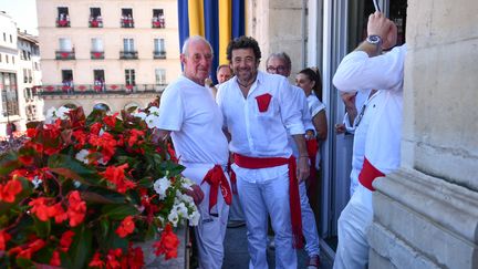 Patrick Bruel, en habit traditionnel des Fêtes de Bayonne, pose à côté de l'ancien footballeur Jean-Claude Larrieu. (GAIZKA IROZ / AFP)