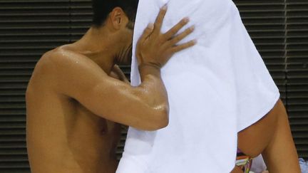 Bisous vol&eacute; entre les nageurs italiens Federica Pellegrino et Filippo Magnini &agrave; la piscine olympique, le 26 juillet, &agrave; la veille de l'ouverture des Jeux olympiques.&nbsp; (DAVID GRAY / REUTERS)