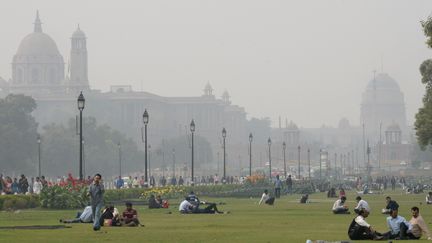 Des personnes se détendent, le 2 décembre 2015, sur les pelouses du Rajpath, à New Delhi (Inde), devant&nbsp;les bâtiments du gouvernement enveloppés d'un épais brouillard. (PRAKASH SINGH / AFP)