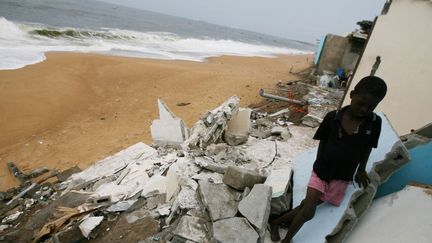 Un enfant marche dans les gravats de ce qui était une maison détruite par les flots à Port Bouet en Côte d'Ivoire le 14 août 2007. (SIA KAMBOU / AFP)