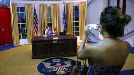 Le top &eacute;tant de se faire photographier dans le bureau ovale de la Maison Blanche, reproduit fid&egrave;lement dans le cadre d'une exposition itin&eacute;rante install&eacute;e pour l'occasion aux abords de la convention d&eacute;mocrate. (JOE RAEDLE / GETTY IMAGES / AFP)